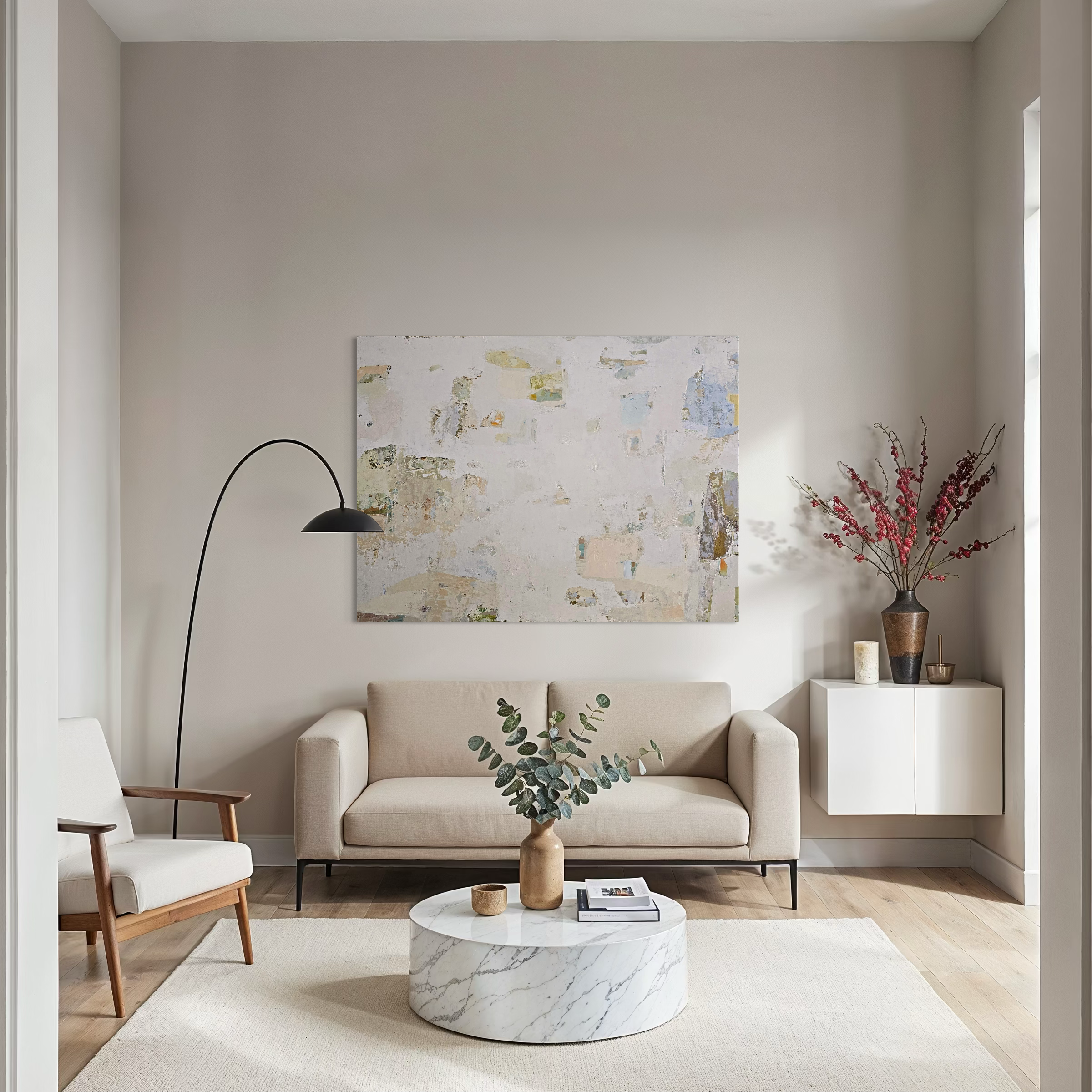 A styled living room interior featuring a large abstract canvas painting with beige, white, and muted neutral tones hanging above a light beige sofa. 