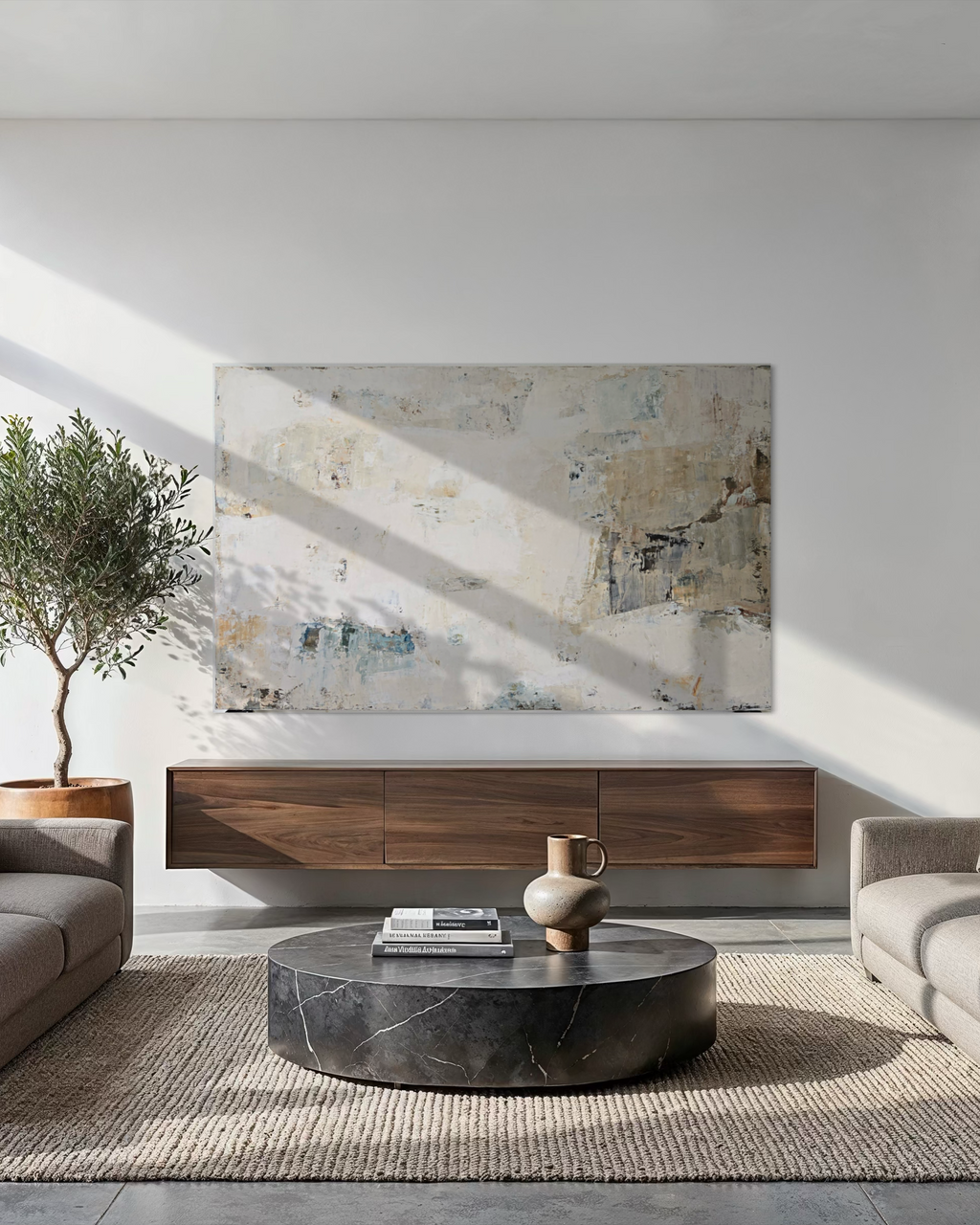 A large abstract canvas painting created by Birute Studio with textured layers in neutral, beige, gray, and muted blue, displayed in a modern living room setting above a floating dark wood console.