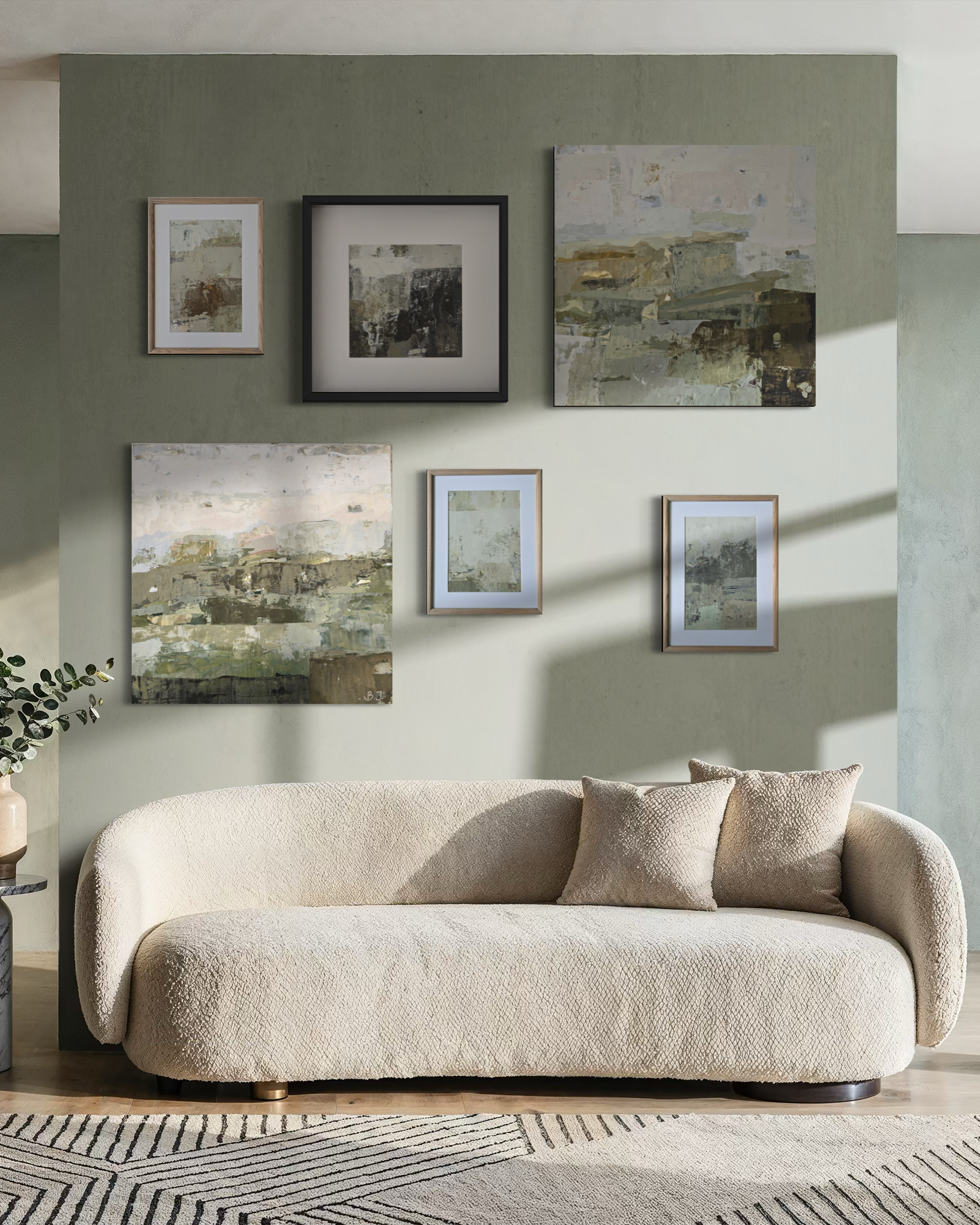 A cream bouclé sofa in a styled living room setting, positioned beneath a gallery wall of six abstract paintings created by Birute Studio on a sage green wall.